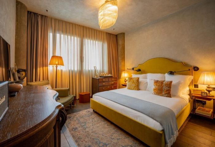 Soho House Istanbul gay-friendly hotel room. Stylish bedroom with a yellow bed, vintage furniture, and warm lighting. Luxury gay travel.