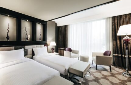 Elysium Taksim Hotel room with two beds, chairs, and lamps. Gay-friendly hotel with modern decor, ideal for gay travelers in Istanbul.