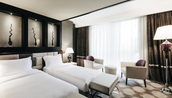 Elysium Taksim Hotel room with two beds, chairs, and lamps. Gay-friendly hotel with modern decor, ideal for gay travelers in Istanbul.