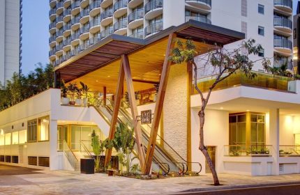 The Laylow, Autograph Collection, a gay-friendly hotel. Exterior view with escalators, wood accents, and tropical plants. Waikiki, Hawaii hotel.