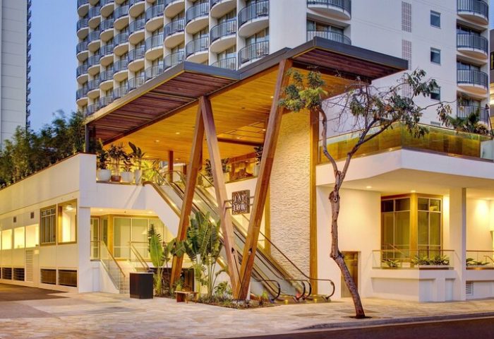 The Laylow, Autograph Collection, a gay-friendly hotel. Exterior view with escalators, wood accents, and tropical plants. Waikiki, Hawaii hotel.
