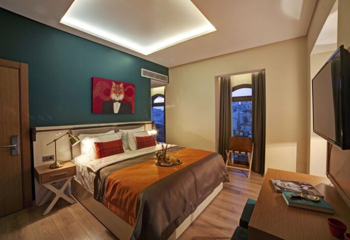 The Fox Hotel gay-friendly room. Bed with fox art, window view, and TV. Stylish, modern decor. Perfect for gay men's travel.