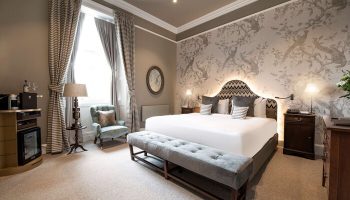 Schloss Roxburghe Hotel gay-friendly suite. King bed, bird-themed wallpaper, & stylish decor. A luxury stay for gay travelers.