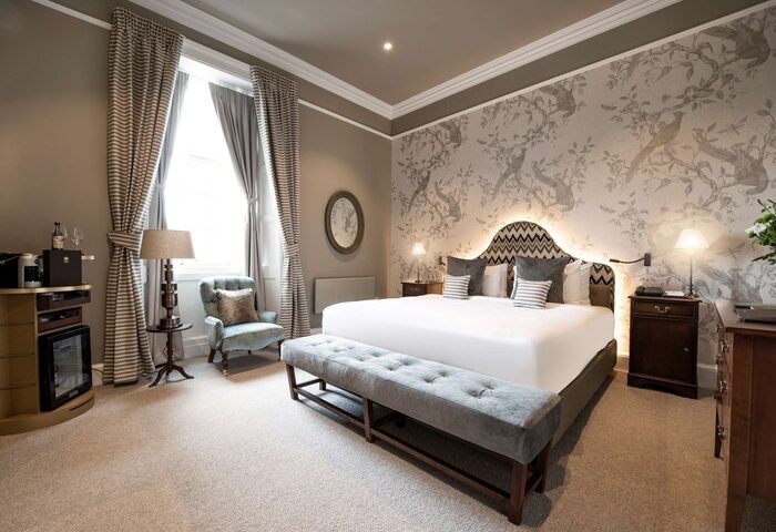 Schloss Roxburghe Hotel gay-friendly suite. King bed, bird-themed wallpaper, & stylish decor. A luxury stay for gay travelers.