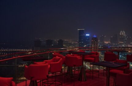 W Dubai - Mina Seyahi gay-friendly hotel rooftop bar at night. Red chairs and tables overlook the Dubai skyline. Gay travel advice.
