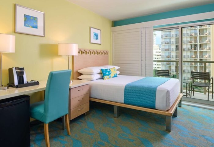 Aston Waikiki Circle Hotel room. Gay-friendly hotel with a bed, desk, balcony, and city view. Waikiki travel advice for gay men.