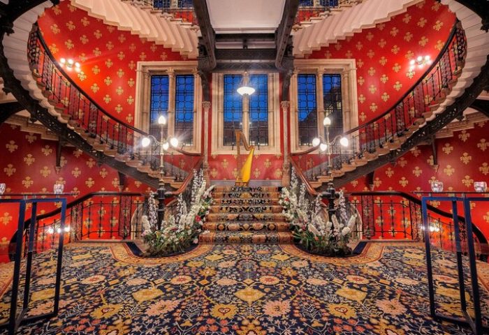 St. Pancras Renaissance Hotel London's grand staircase. This gay-friendly hotel features a harp, floral arrangements, and ornate decor.