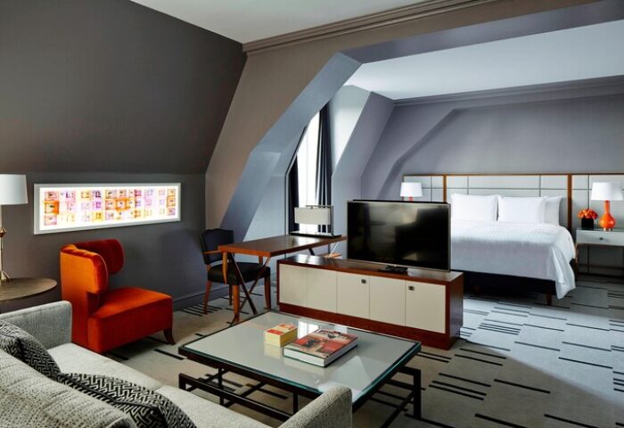 London Marriott Hotel County Hall gay-friendly room. Modern design, gray walls, orange chair, and a comfortable bed. Gay travel advice.