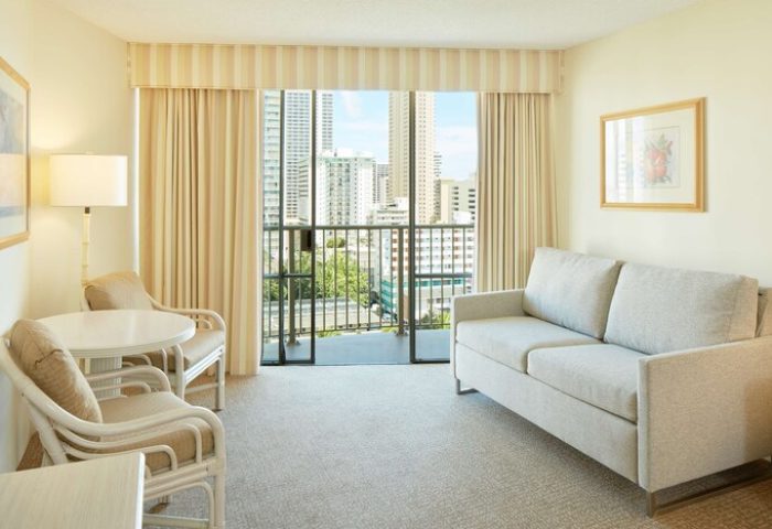 OHANA Waikiki East by OUTRIGGER room. Gay-friendly hotel with balcony, city view, sofa, table, and chairs. Ideal for gay men's travel in Waikiki.