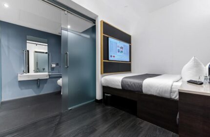 The Z Hotel Trafalgar gay-friendly room. Modern design with a bed, TV, and accessible bathroom with sliding glass door. Ideal for gay men travel.
