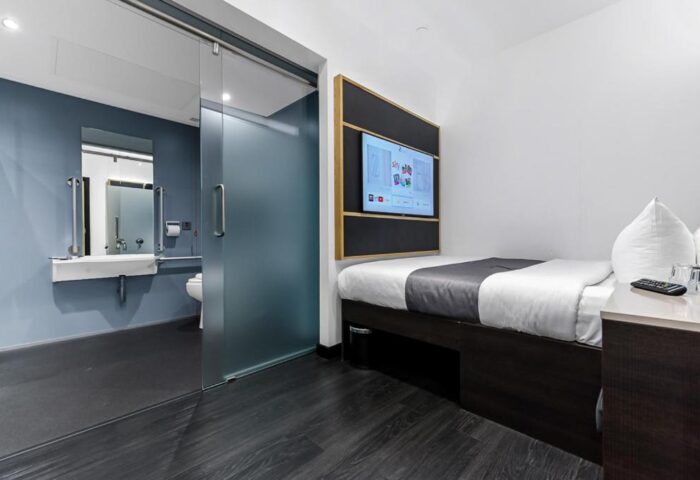 The Z Hotel Trafalgar gay-friendly room. Modern design with a bed, TV, and accessible bathroom with sliding glass door. Ideal for gay men travel.
