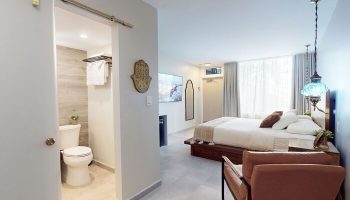 Bedroom suite at gay-friendly The Grand Resort and Spa, all-male spa resort. Modern design with bathroom, bed, and seating area.