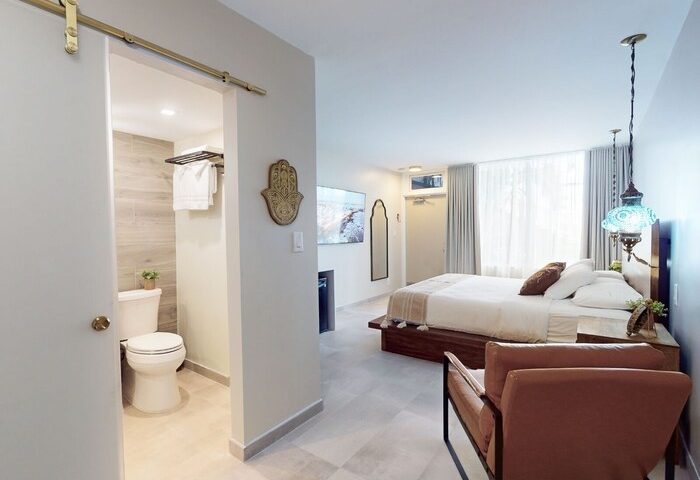 Bedroom suite at gay-friendly The Grand Resort and Spa, all-male spa resort. Modern design with bathroom, bed, and seating area.