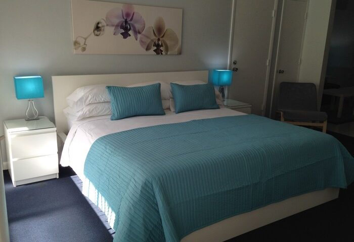 Bedroom at Cheston House, a gay-friendly hotel. Room features a bed with blue accents, bedside tables, and artwork. All-male guesthouse.
