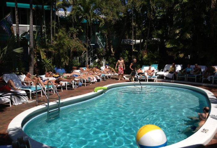 Pool scene at Pineapple Point Guesthouse & Resort, a gay men's resort. Men lounge poolside, sunbathing and relaxing at this gay-friendly hotel.