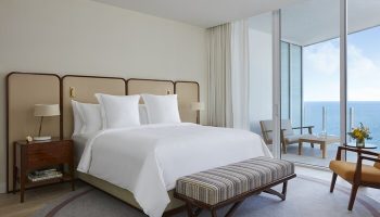 Four Seasons Hotel and Residences Fort Lauderdale room with ocean view. Gay-friendly hotel with balcony. Bed, bench, and chairs.