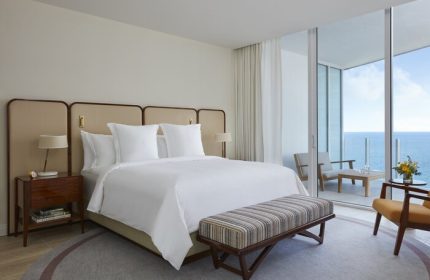 Four Seasons Hotel and Residences Fort Lauderdale room with ocean view. Gay-friendly hotel with balcony. Bed, bench, and chairs.