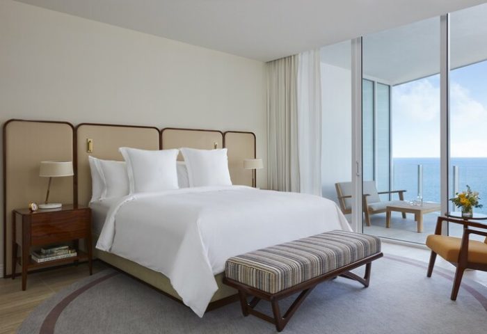 Four Seasons Hotel and Residences Fort Lauderdale room with ocean view. Gay-friendly hotel with balcony. Bed, bench, and chairs.