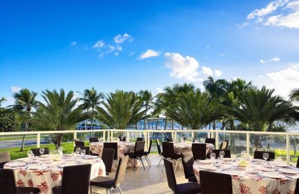 Sonesta Fort Lauderdale Beach gay-friendly hotel outdoor event space. Tables set with coral-themed linens, ocean view, and palm trees.