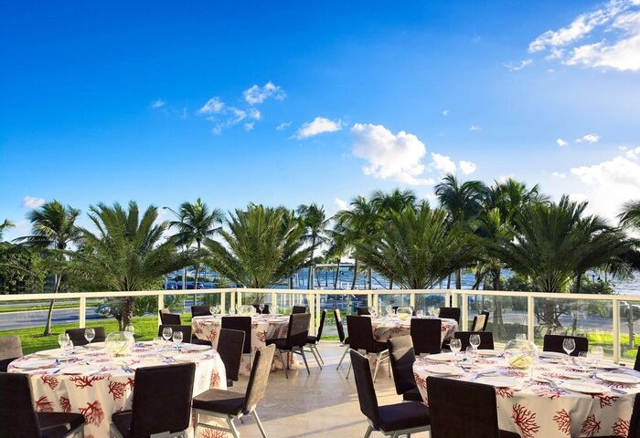 Sonesta Fort Lauderdale Beach gay-friendly hotel outdoor event space. Tables set with coral-themed linens, ocean view, and palm trees.