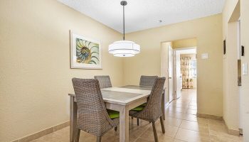 Dining area at Coconut Bay Resort, a gay-friendly hotel. Table with four chairs, modern light fixture, and artwork. Interior of gay hotel room.
