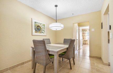 Dining area at Coconut Bay Resort, a gay-friendly hotel. Table with four chairs, modern light fixture, and artwork. Interior of gay hotel room.