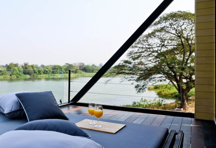 Cross River Kwai gay-friendly hotel. River view from a luxurious room. Two orange juices on a tray. Relaxing at X2 River Kwai.
