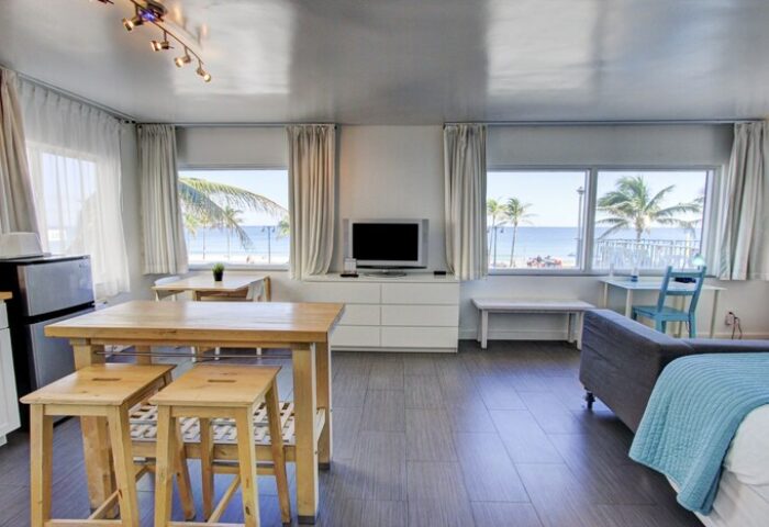 Gay-friendly hotel room with beach view. Interior of a modern apartment featuring a living area, kitchen, and windows overlooking the ocean.