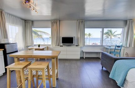 Gay-friendly hotel room with beach view. Interior of a modern apartment featuring a living area, kitchen, and windows overlooking the ocean.