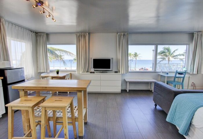 Gay-friendly hotel room with beach view. Interior of a modern apartment featuring a living area, kitchen, and windows overlooking the ocean.