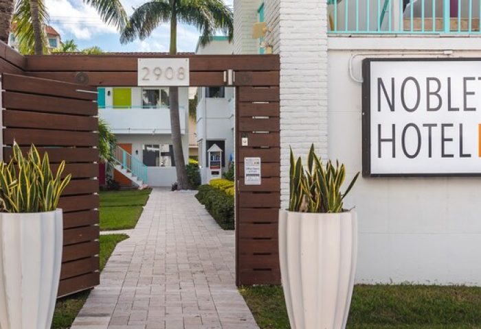 Nobleton Hotel entrance. Gay-friendly hotel with colorful accents. Inviting walkway, lush greenery, and modern design. Perfect for gay travel.