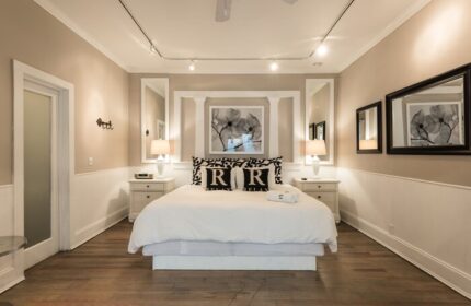 Alexander's Guesthouse gay-friendly hotel room. Bedroom with white bedding, bedside tables, and mirrors. Relax at this gay travel destination.