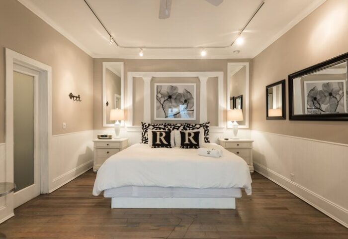Alexander's Guesthouse gay-friendly hotel room. Bedroom with white bedding, bedside tables, and mirrors. Relax at this gay travel destination.
