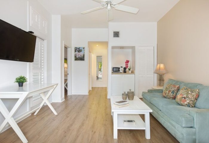 Paradise Inn adults only gay-friendly hotel room. Living space with sofa, table, TV, and kitchenette. Ideal for gay travel and relaxation.