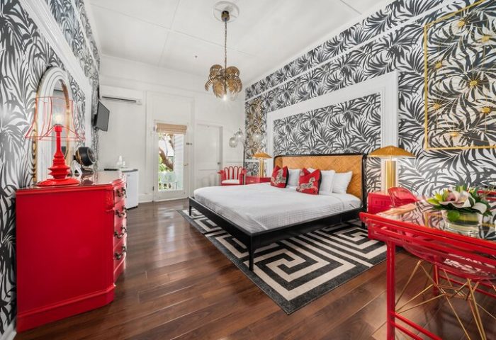 Marrero's Guest Mansion gay-friendly hotel room. Red accents, patterned wallpaper, king bed, and stylish decor for gay men's travel.