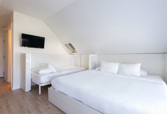 NYAH Key West adults-only, gay-friendly hotel room. Clean, white interior with a king bed, a twin bed, and a flat-screen TV.