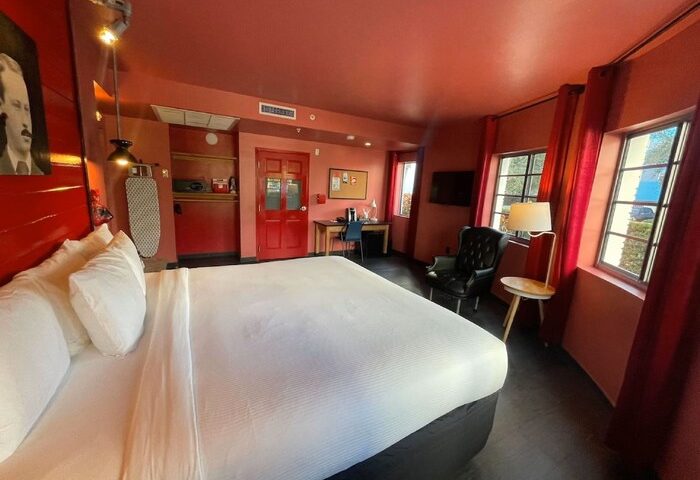Hotel Gaythering's gay-friendly room. All adults welcome. Red themed room with a large bed, desk, and windows. Gay hotel interior.