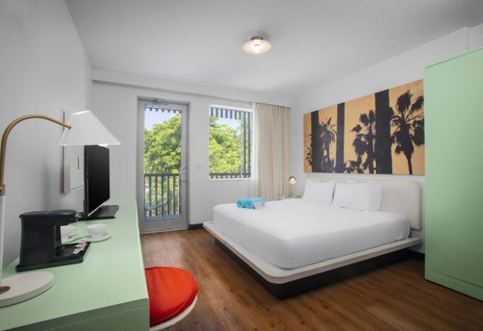 Axel Beach Miami gay-friendly hotel room. Modern design, white linens, palm tree art, balcony view. A stylish stay for gay travelers.