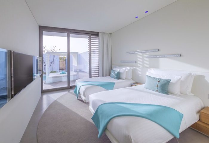 Nikki Beach Resort & Spa Dubai gay-friendly hotel room. Twin beds with turquoise accents. Modern design, bright, and airy. Perfect for gay travelers.