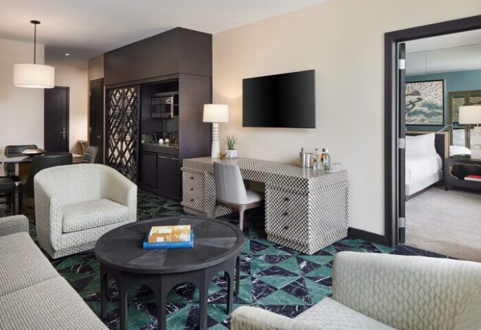 W Miami gay-friendly hotel room. Modern interior with desk, TV, seating area, and bedroom view. Luxury travel and accommodation for gay men.