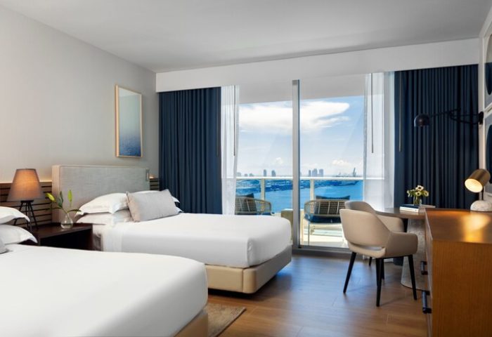 Kimpton EPIC Hotel gay-friendly room with two beds, desk, and balcony overlooking the ocean. Miami gay travel lodging option.