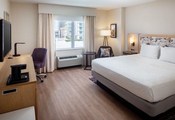 Hampton Inn & Suites Miami/Brickell-Downtown gay-friendly hotel room. Features a bed, desk, chair, TV, and city views. Modern, comfortable space.