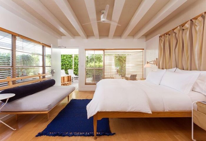 The Standard Miami gay-friendly hotel room. Modern decor, king bed, daybed, blue rug, and outdoor access. Perfect for gay travel.