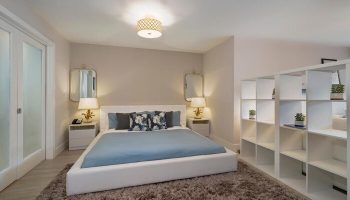 Strand Ocean Drive Suites bedroom. Gay-friendly hotel room with a white bed, blue linens, and a bookshelf. Perfect for gay travel in Miami.