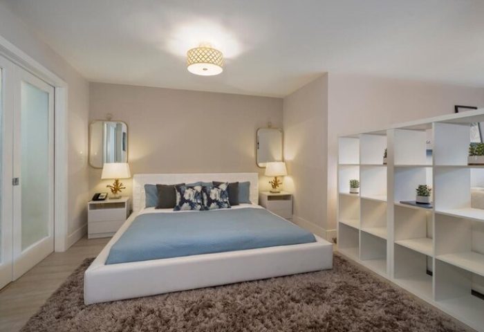 Strand Ocean Drive Suites bedroom. Gay-friendly hotel room with a white bed, blue linens, and a bookshelf. Perfect for gay travel in Miami.