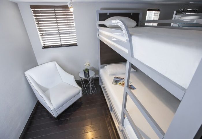 Posh South Beach gay-friendly hotel room with bunk beds, white chair, and modern design. A comfortable stay for gay travelers in South Beach.