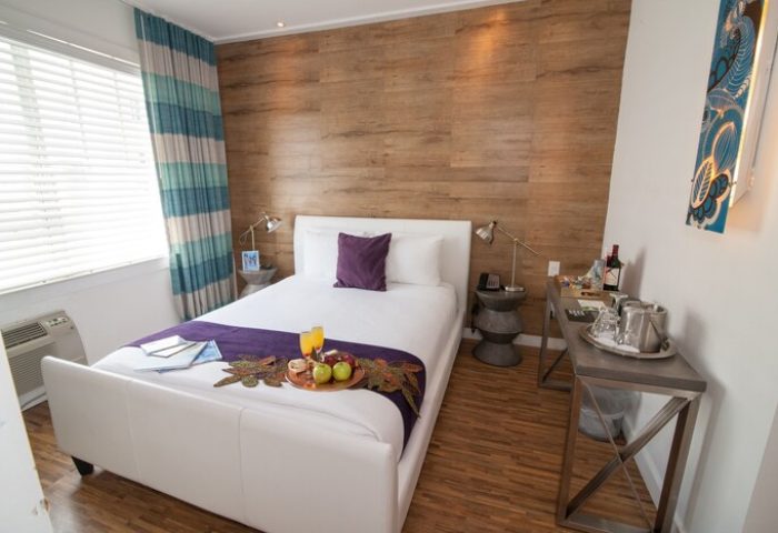 Hotel Shelley's gay-friendly room: white bed with breakfast tray, wood-look wall, stylish decor. A welcoming space for LGBTQ+ travelers.