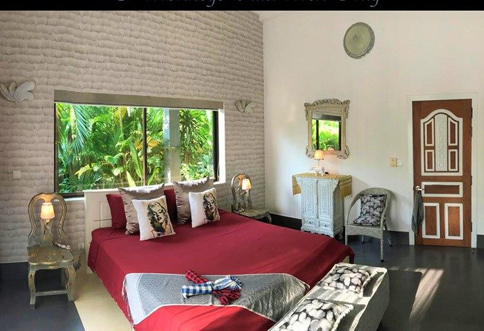3 Monkeys Villa gay hotel room. Pet-friendly, gay-friendly hotel with red bed, Marilyn Monroe pillows, and garden view. Gay travel lodging.