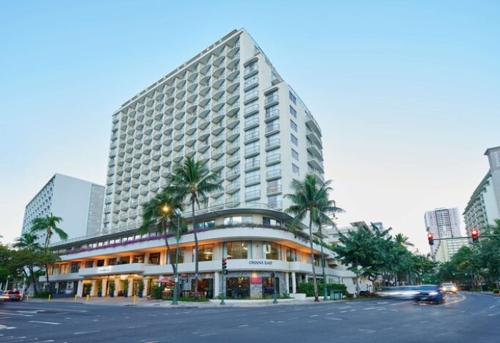 OHANA Waikiki East by OUTRIGGER, a gay-friendly hotel. Exterior view of the hotel, palm trees, and street scene. Waikiki gay travel.