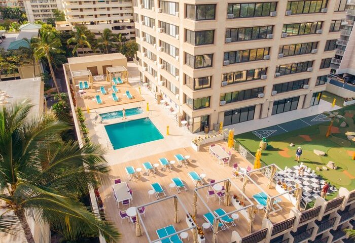 Holiday Inn Express Waikiki rooftop pool and lounge area. Gay-friendly hotel with sunbeds, tables, and a giant chessboard for an inclusive vacation.